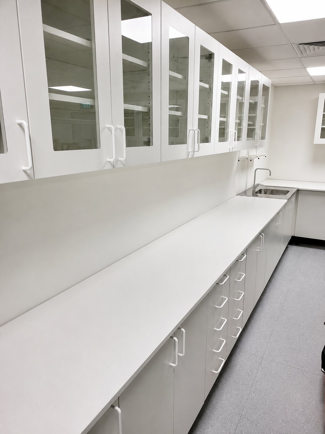 Laboratorieinredning — vita överskåp i korridor